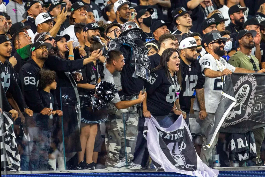 Raiders fans wave black and silver flags at Gillette Stadium.
