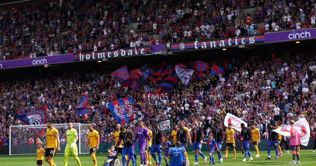 Crystal Palace players walk out onto the pitch under the bright lights at Selhurst Park.
