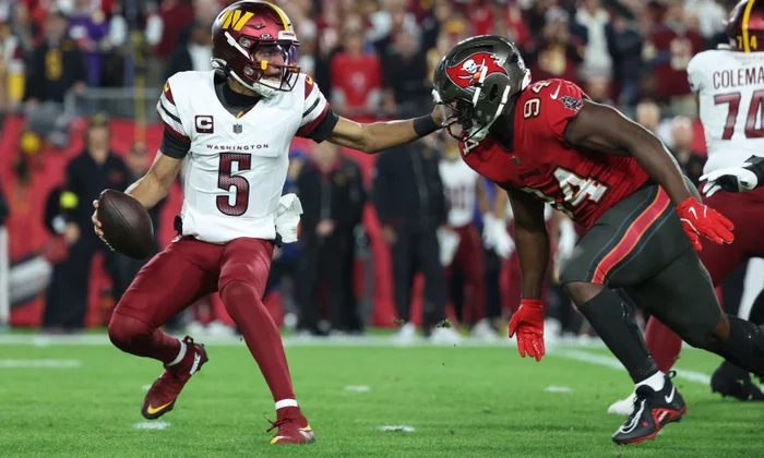 Josh Allen launching a deep ball over Lamar Jackson rushing up front.