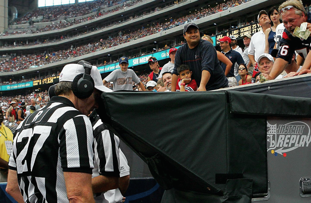 Referees sitting around a monitor reviewing the play