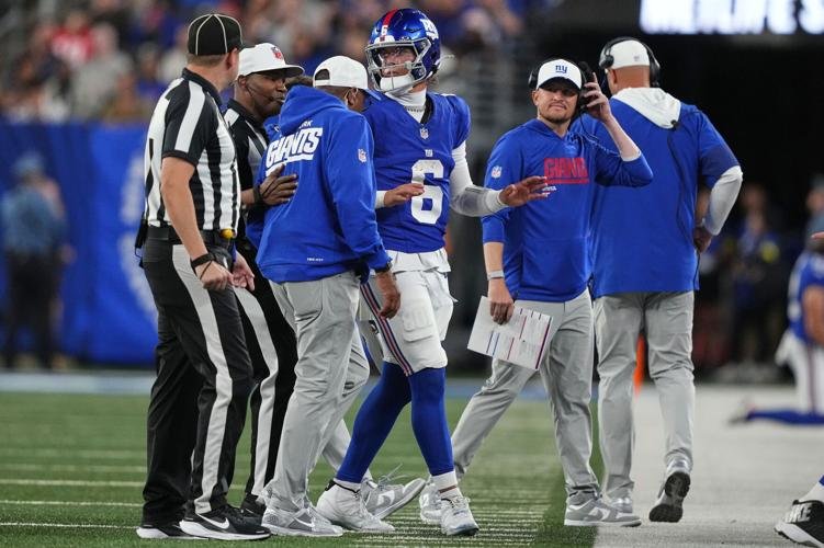 Dart throwing a pass at a Giants practice or preseason game, with coaches watching from the sideline.