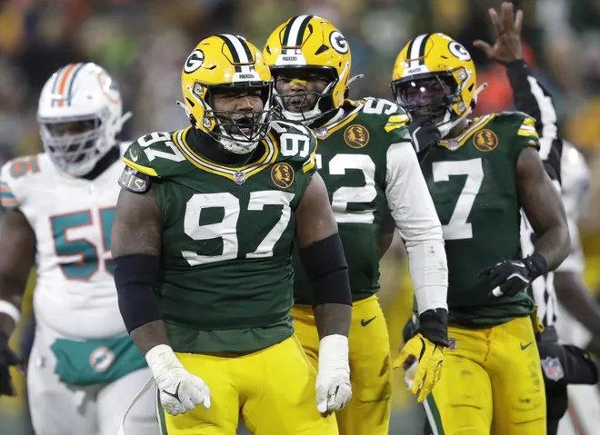 Kenny Clark sacking a quarterback in his Packers uniform.