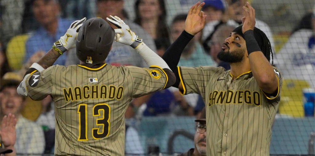 Padres players celebrate together after the final out, fans in the stands are stunned.