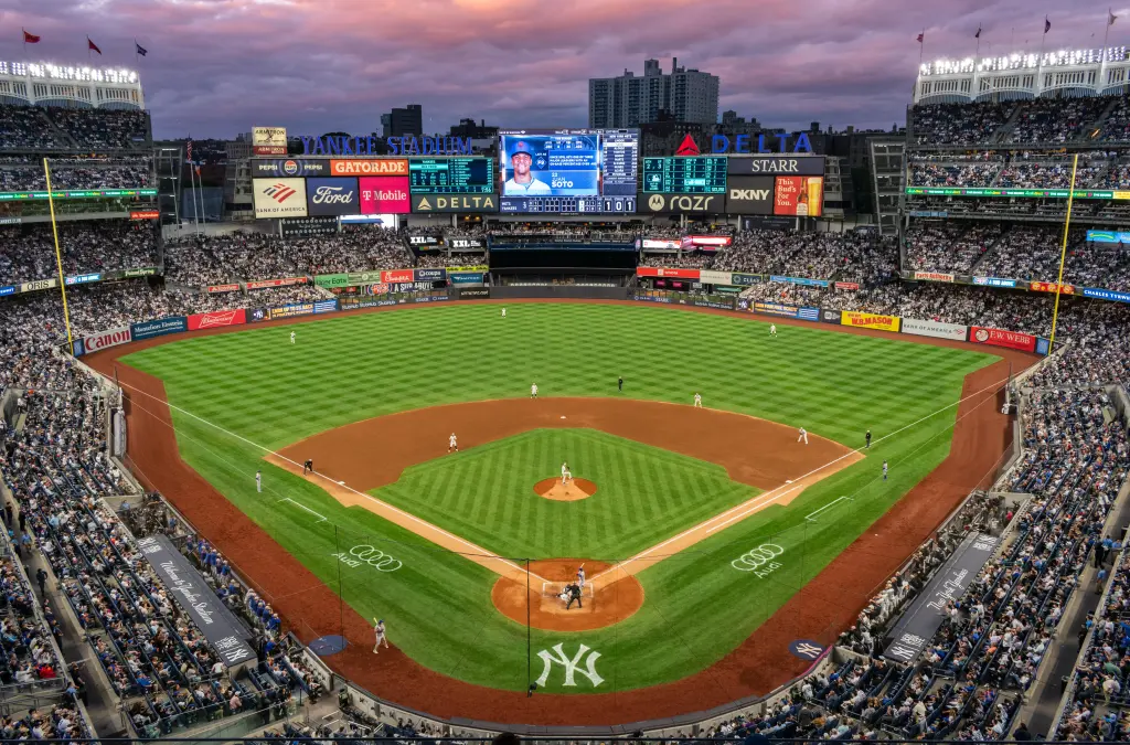 A dramatic split-screen of Yankee Stadium, Fenway Park and Rogers Centre under the heading "AL East 2025 Battle."