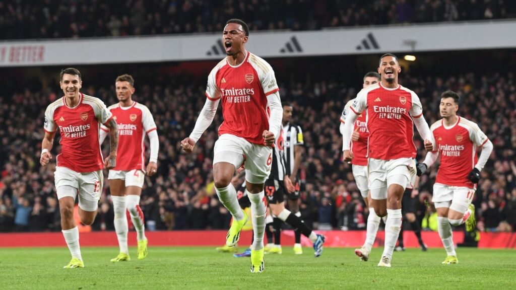 Arsenal players celebrate a goal at a packed Emirates Stadium.