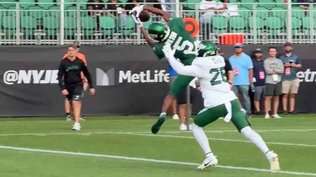 Garrett Wilson is leaping for the catch and T.J. Watt is putting pressure on Fields.