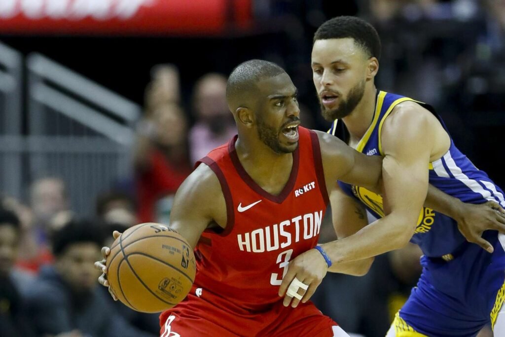 Chris Paul mid-dribble, defenders closing in, ball bouncing toward Curry.